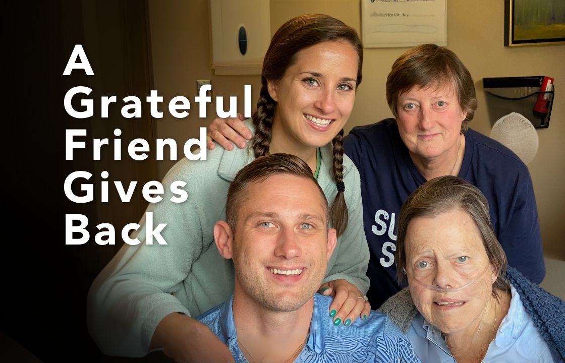 A hospice patient in a blue robe with an oxygen cannula in her nose is surrounded by family and friends