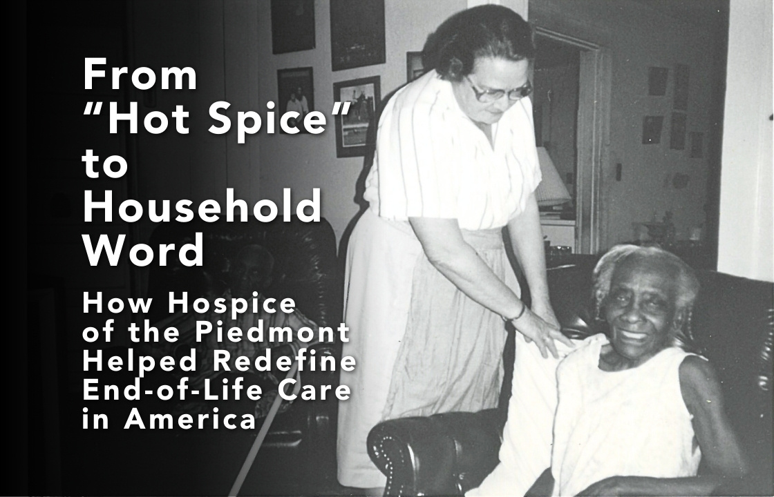 Black and white photo from 1986 a white woman wearing a white blouse, skird and striped apron adjusts the pillow behind a older frail black woman seated on a couch.