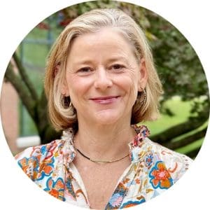 Julie King wears a floral shirt and stands in front of a natural landscape